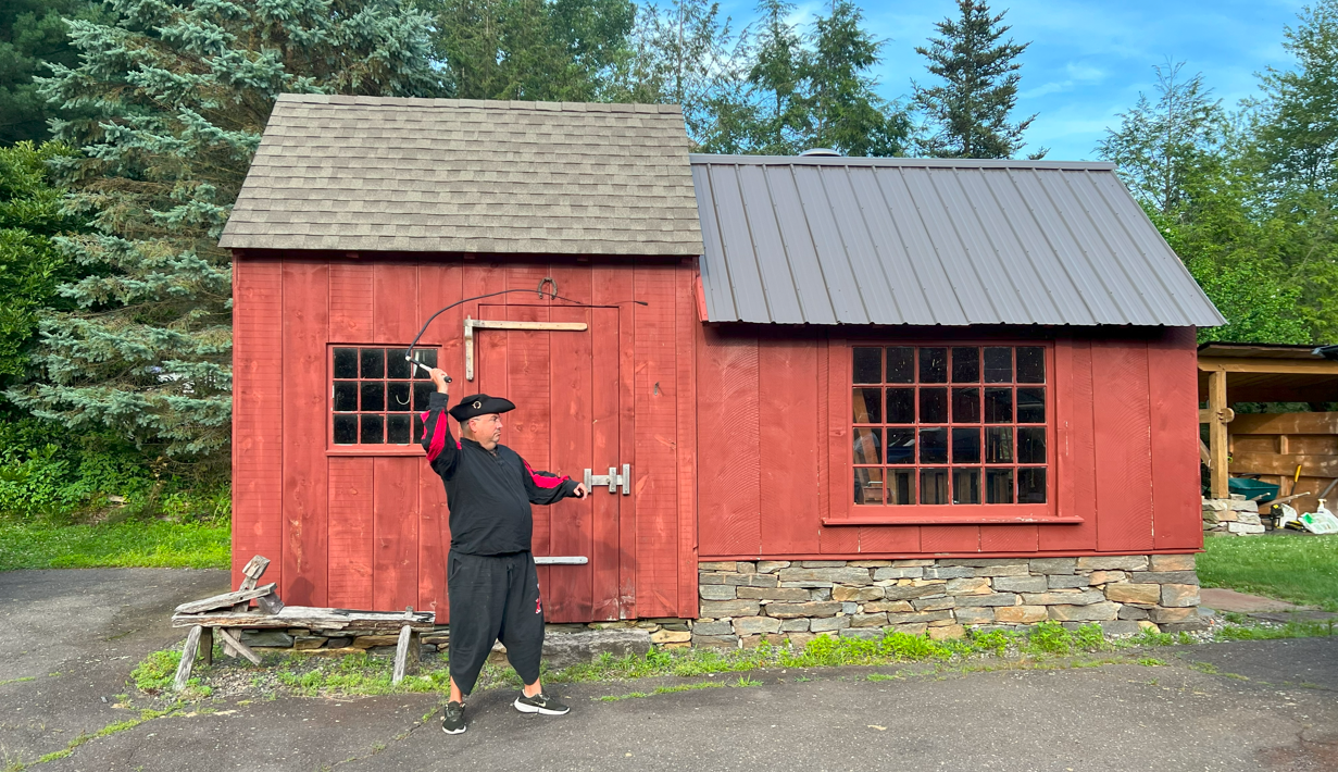 Jack Hazzah cracking a whip in front of a red building